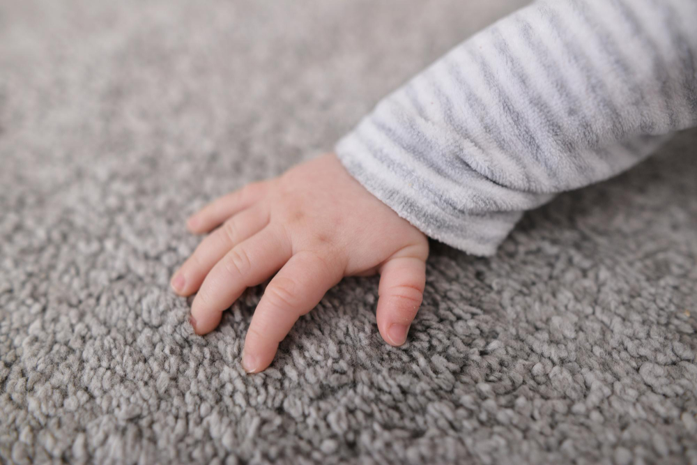 main de bébé touchant de la moquette grise