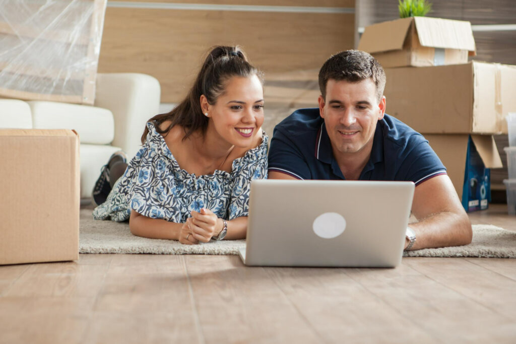 Un jeune couple choisissant une assurance de prêt immobilier sur un ordinateur portable