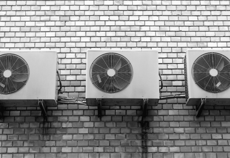 trois climatiseurs attachés au mur d'un bâtiment