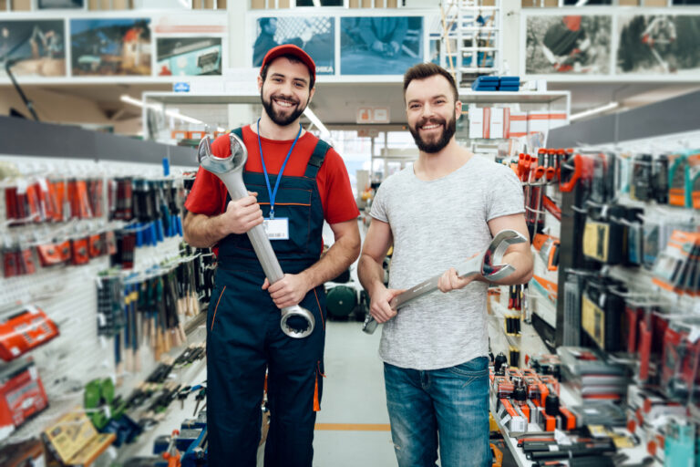 Deux vendeurs tenant de grands outils dans un magasin de bricolage