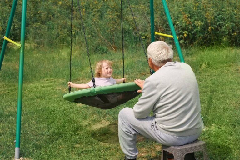 un grand père pousse sa petite fille sur une balançoire