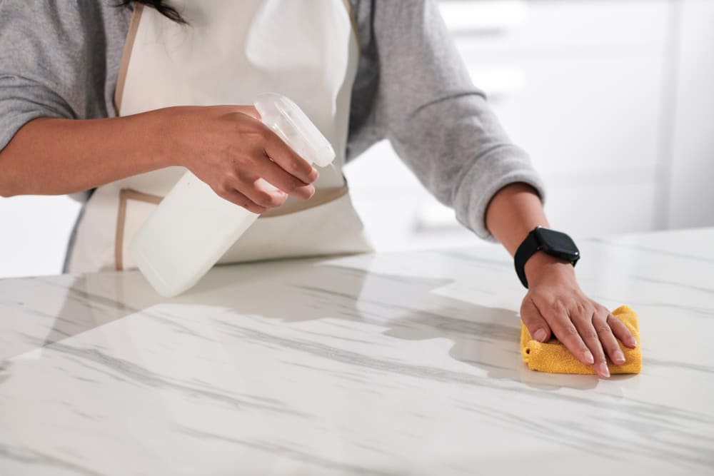 Nettoyage d'une surface en marbre blancavec un chiffon en microfibre et un produit adapté