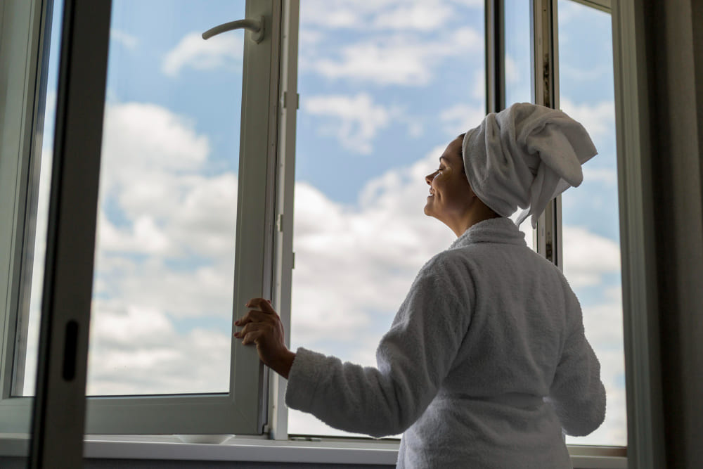 une femme ouvre une fen&ecirc;tre pvc
