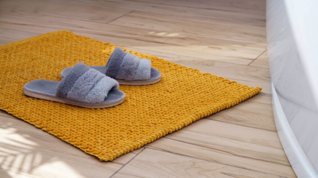 Tapis de bain textile jaune devant une baignoire