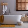 Tapis de bain absorbant plac&eacute; devant une baignoire moderne
